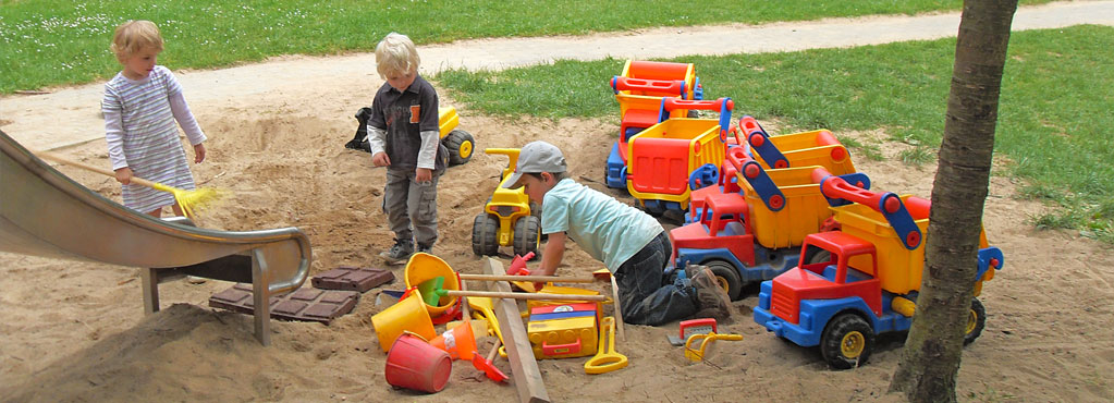 Bild 3 zeigt drei Kinder die im Sandkasten spielen mit vielen Sandspielsachen.