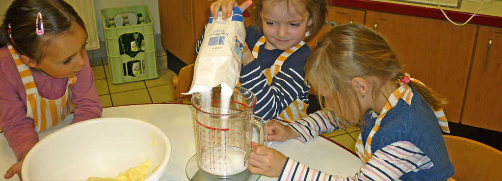 Bild 4 zeigt drei Mädchen, die zusammen in der Küche backen.
